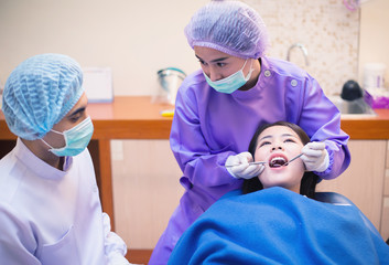 Dentist, his assistant and the patient are preparing to treat carious teeth in the dental clinic