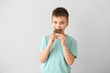 © Pixel-Shot - Cute little boy eating chocolate on light background