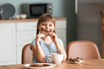 Wall Mural - Cute little girl eating chocolate in kitchen