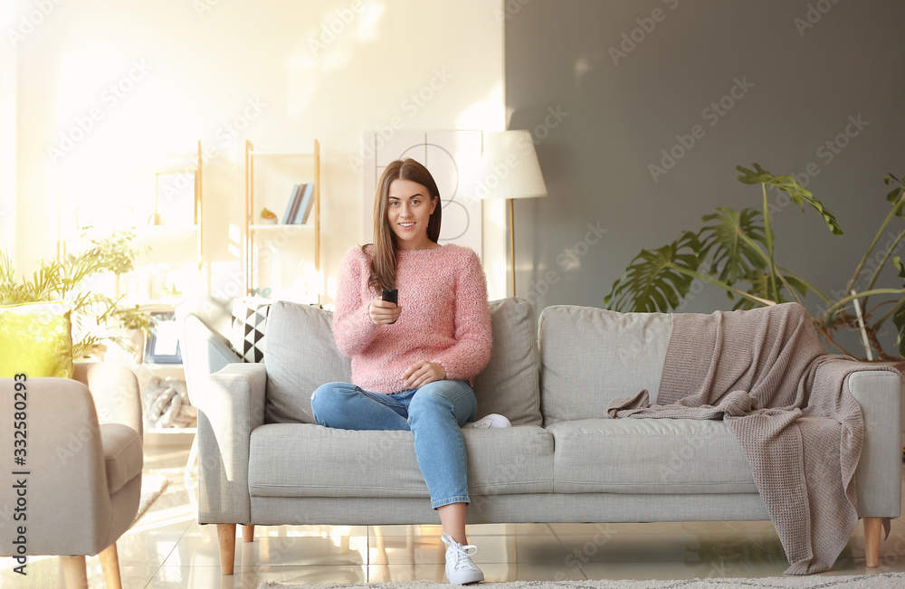 Beautiful young woman watching TV at home