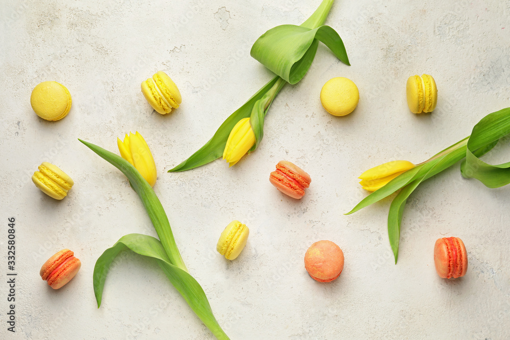 Tasty macarons with tulip flowers on white background