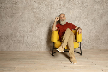 Portrait of bearded senior man relaxing in sofa at home.