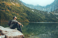 Man Sitting On The Rock In Front Of Lake In Mountains Enjoying The View