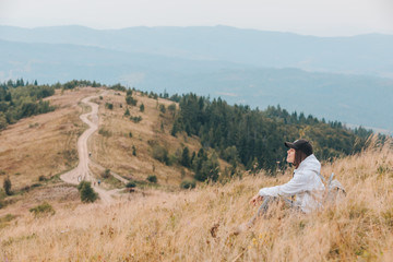 Poster - woman sitting on the ground looking at mountains hiking concept