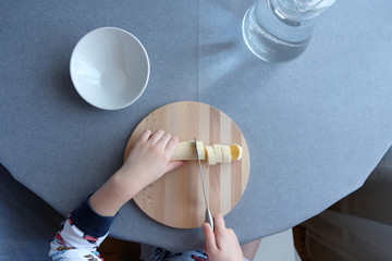 a 6 year old child cutting a ripe banana on grey background