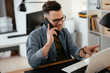 © JustLife - Businessman in office. Handsome man talking on phone at work.
