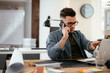 © JustLife - Businessman in office. Handsome man talking on phone at work.