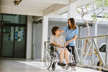 Smiling physiotherapist  taking care of the happy senior patient in wheelchair