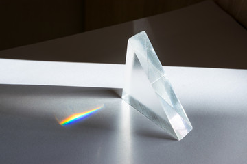 sunlight passes through a prism, causing the light to refract and spread, creating a spectrum of col
