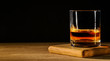 © Soho A studio - Glass with whiskey on wooden table and black background. Copy space.