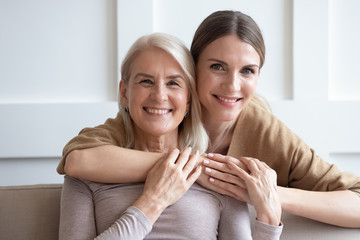 Wall Mural - head shot portrait happy loving adult daughter hugging older mother, smiling young woman and mature 