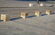 Detail Of Beige-colored Granite Tiles Laid In Rows Straight On It Stands Stone Blocks As A Roadblock Against Car Traffic Or Pavement Protection