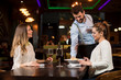 © BGStock72 - Smiling young female friends at a restaurant with waiter serving dinner