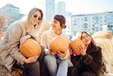 Fototapeta Londyn - Girls holds pumpkins in hands on the background of the street.
