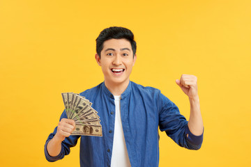 Portrait of excited amazed wondered astonished cheerful rejoicing manager showing many banknotes isolated on yellow background