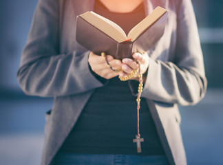 Wall Mural - Close-ups of beautiful Asian beautiful girls are reading the sacred Bible and praying from God. In her hands, there is a cross necklace that symbolizes redemption for the people of Jesus. copy space.