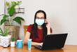 © Phuttharak - woman wearing hygienic disposable mask sitting at  table with computer laptop , alcohol sanitizer hand gel , talking on mobile phone, working from home concept.protection from corona virus or covid-19