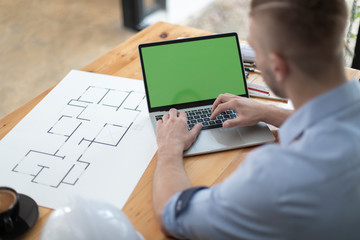 Close-up Architect or engineer hands using tablet working on blueprint plans  with  a pencil,  a ruler, calculator, smartphone, laptop and engineering tools.