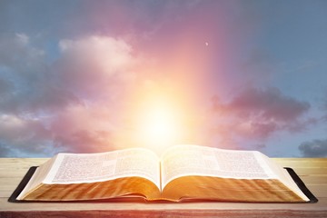 Wall Mural - open book on old wooden table on sky background