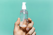 © Lalandrew - Close-up of male hand holding small plastic bottle of sanitizer antibacterial gel on background of cyan aqua menthe color.