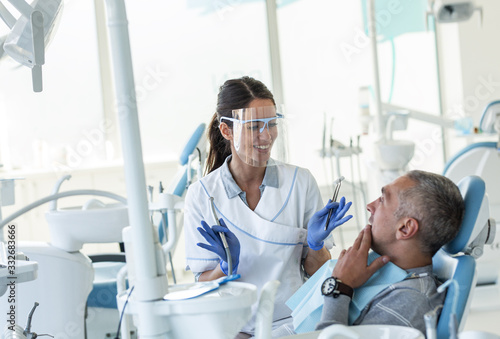 Cuadros en Lienzo Dentist in dental office talking with male patient and preparing for treatment