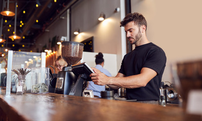 Male Coffee Shop Owner Working Behind Sales Desk