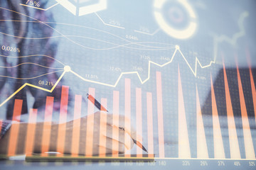 A woman hands writing information about stock market in notepad. Forex chart holograms in front. Concept of research. Double exposure