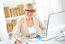 Portrait Of Mature Business Woman Looking At Camera At Workplace In An Office