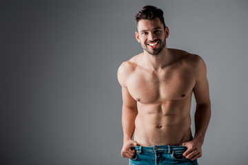 smiling muscular sexy shirtless man in jeans on grey
