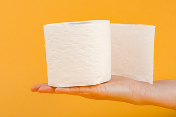 Wall Mural - A roll of toilet paper in a woman's hand on a yellow background