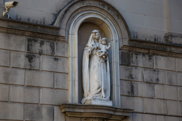 Old sculpture with young woman with child in the arch of the one of old buildings on the La Rambla street in historical center of Barcelona. Spain.