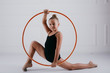 Young rhythmic gymnast with hoop in an acrobatic pose on white background