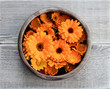 Calendula in a wooden bowl on a wooden table. Flowers calendula collected for drying. Herbal tea marigold buds. Top view