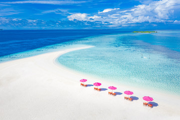 Luxury aerial beach vacation, summer travel and holidays. Loungers, chairs with pink umbrella close to blue sea. Tropical island paradise view, aerial nature landscape