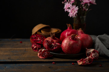 Wall Mural - Several pomegranates on plate on wooden plate and flowers