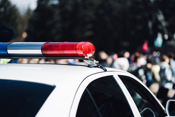 Closeup photo of police car with blue and red siren on the roof and defocused background.