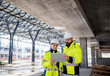 © Halfpoint - Engineers standing outdoors on construction site, using tablet.