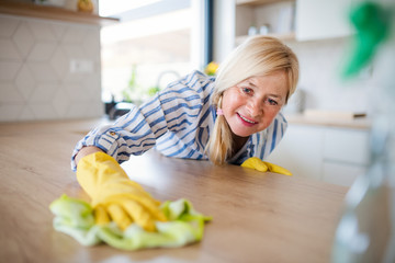 Wall Mural - Portrait of senior woman cleaning kitchen counter indoors at home.