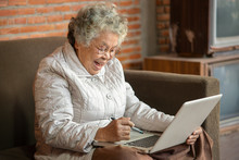 Happy Asian Retired Woman Use Notebook In Living Room At Home.