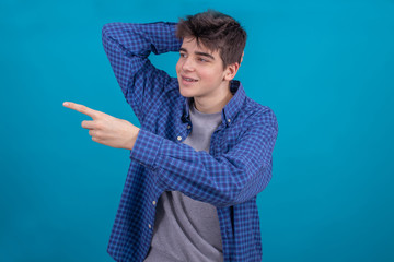 Poster - isolated young male teenager pointing with hand in color background