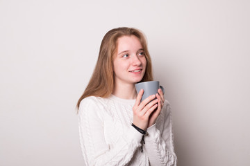 Wall Mural - Positive girl holds a mug of tea. Teen girl drinks from a mug.