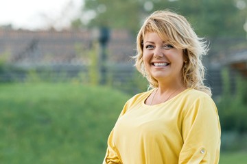 Outdoor portrait successful mature woman blonde in yellow dress