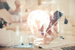 © peshkova - Double exposure of man's hands holding and using a digital device and bulb hologram drawing. Idea concept.