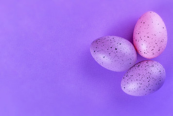  Easter multi-colored eggs on a lilac background
