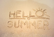© eriksvoboda - Handwritten text hello Summer. Golden sand on tropical beach near sea surf, top view. Background for travel and vacation