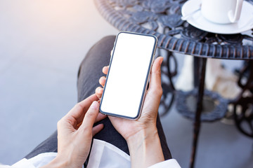 Mockup image blank white screen cell phone.woman hand holding texting using mobile on desk at coffee shop.background empty space for advertise text.people contact marketing business,technology