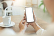 © panitan - Mockup image blank white screen cell phone.woman hand holding texting using mobile on desk at coffee shop.background empty space for advertise text.people contact marketing business,technology