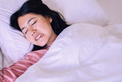 Asian woman sleeping and grinding teeth in bedroom