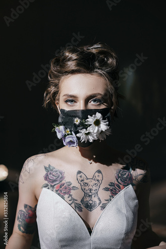 Face of the bride with tattoos in a black medical mask