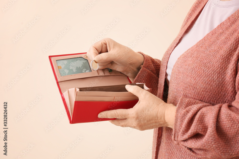 Senior woman with empty wallet on color background